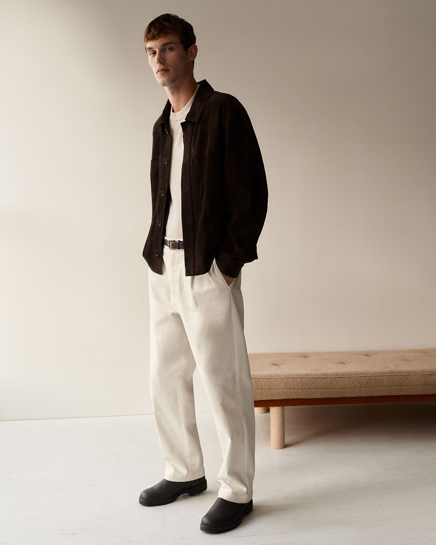 man standing in front of a parachute  with classic beige shorts, white top, and a beige shirt