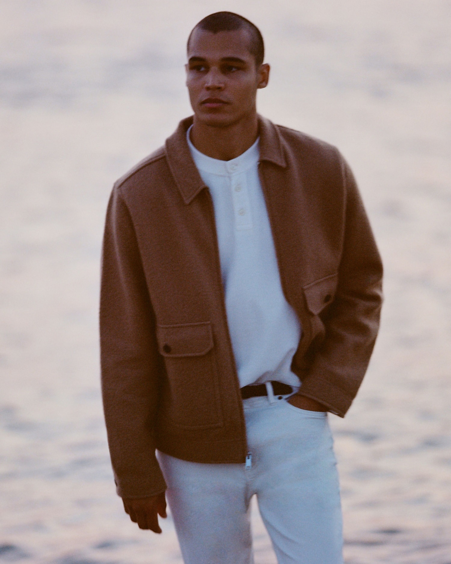 man standing in front of a parachute  with classic beige shorts, white top, and a beige shirt