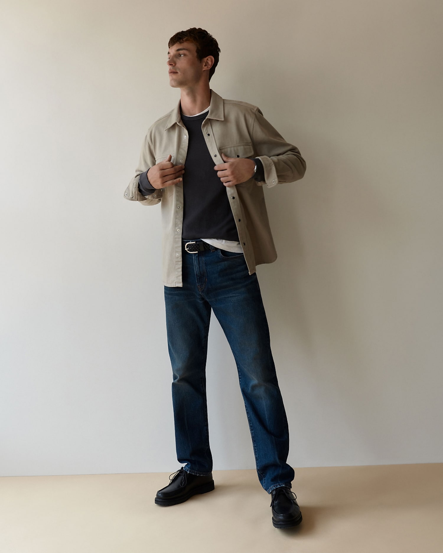 man standing in front of a parachute  with classic beige shorts, white top, and a beige shirt