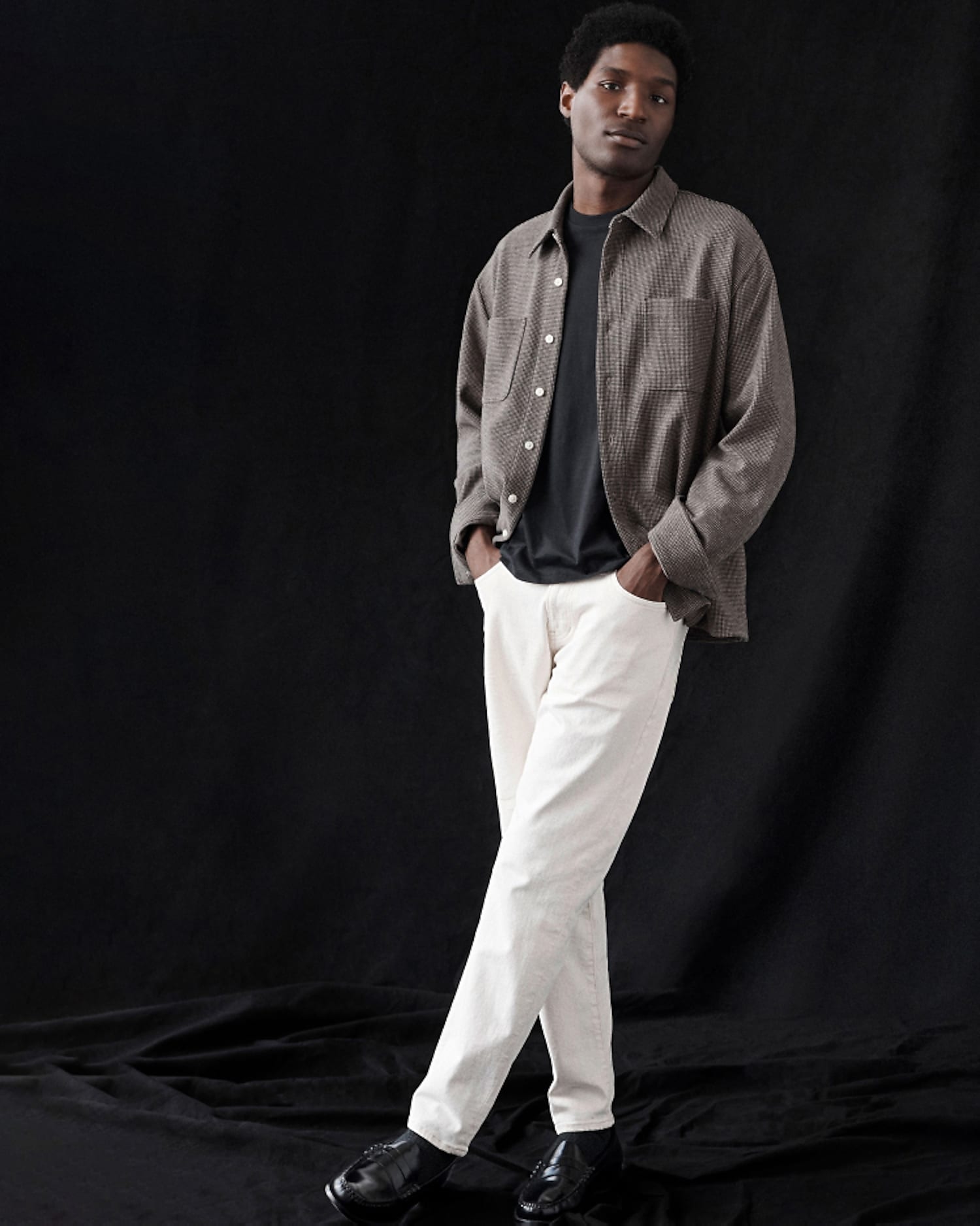 man standing in front of a parachute  with classic beige shorts, white top, and a beige shirt