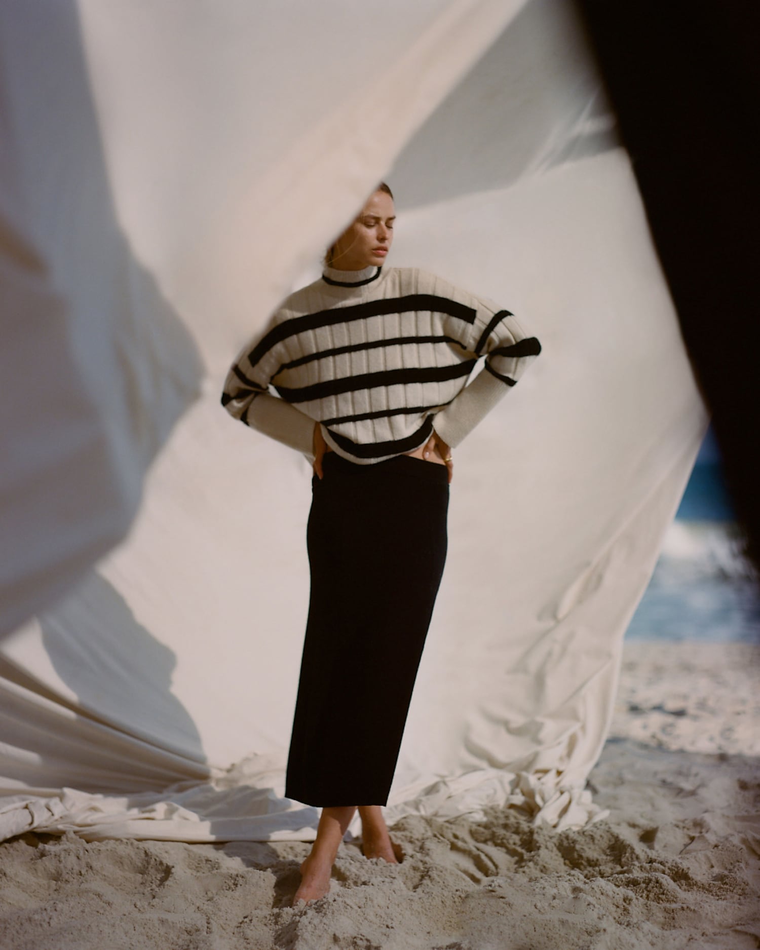 man standing in front of a parachute  with classic beige shorts, white top, and a beige shirt