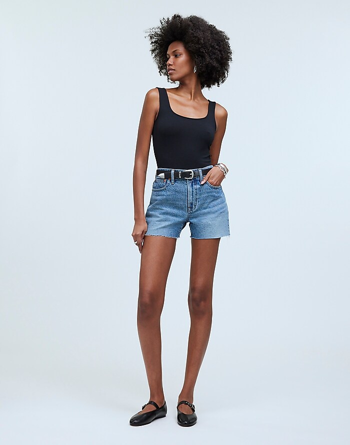 Woman in Black Tank Top and Blue Denim Shorts Standing Near Red